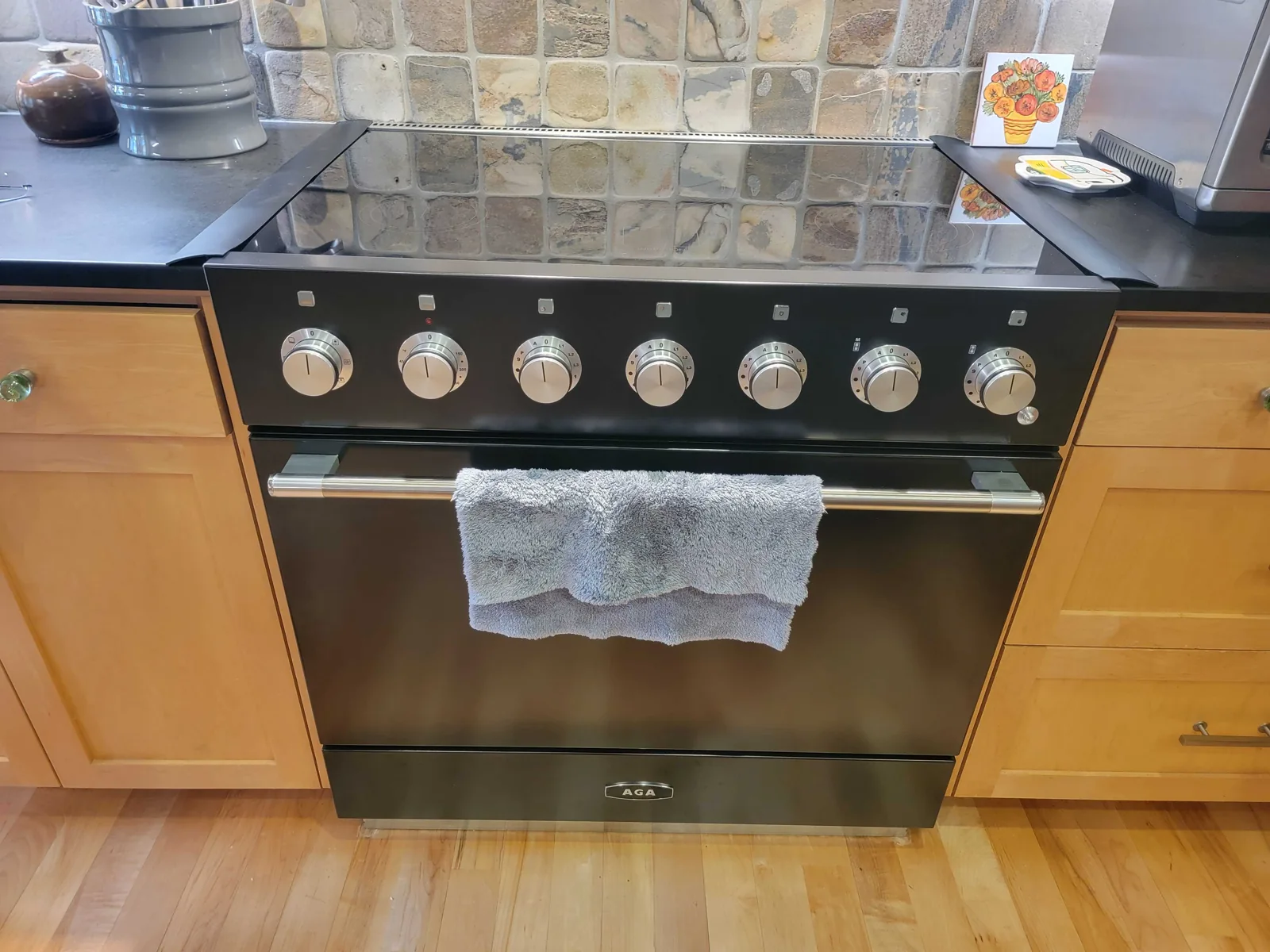 Dark AGA range installed between kitchen cabinets.