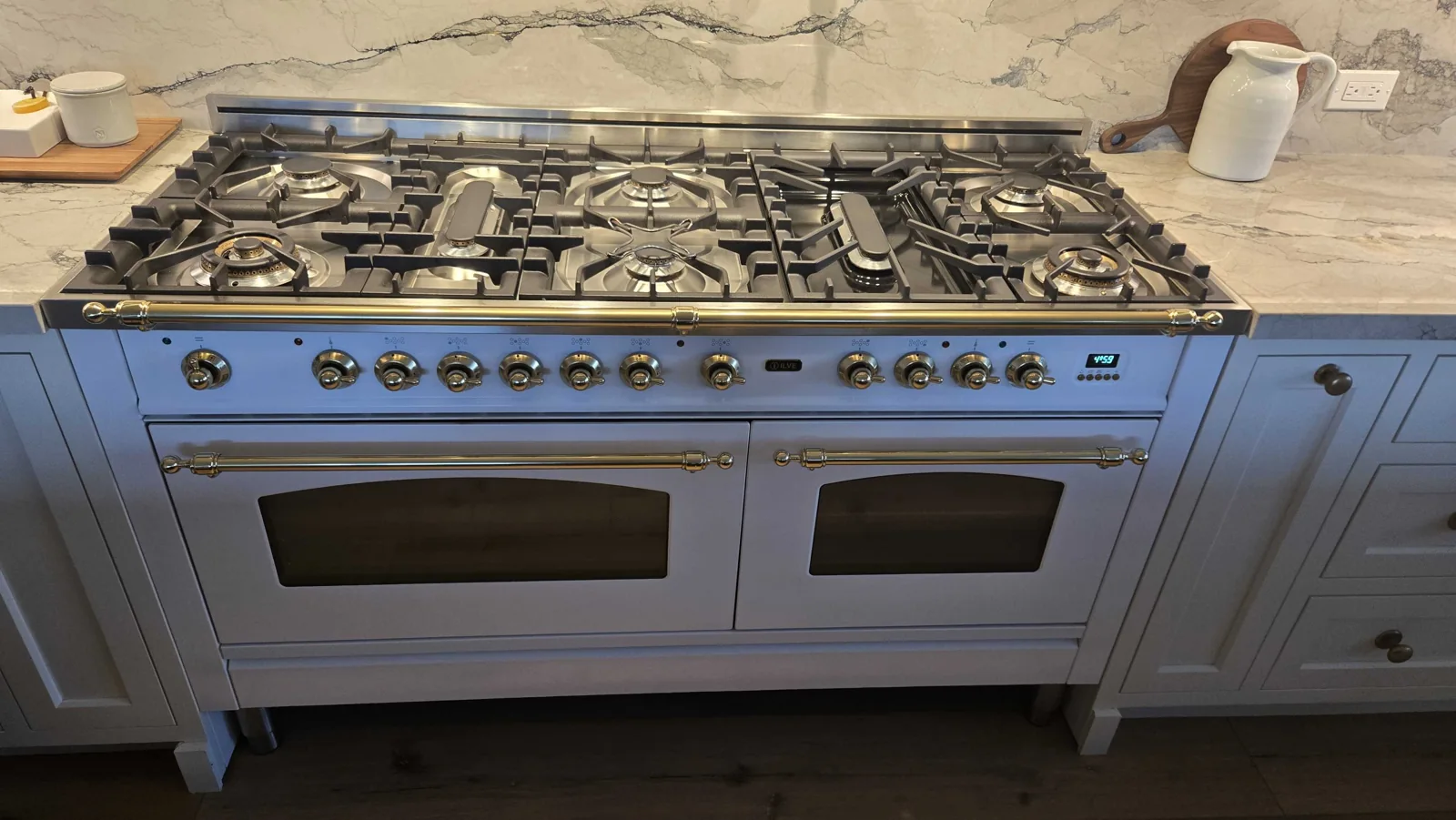 Wide white ILVE range with multiple gas burners.
