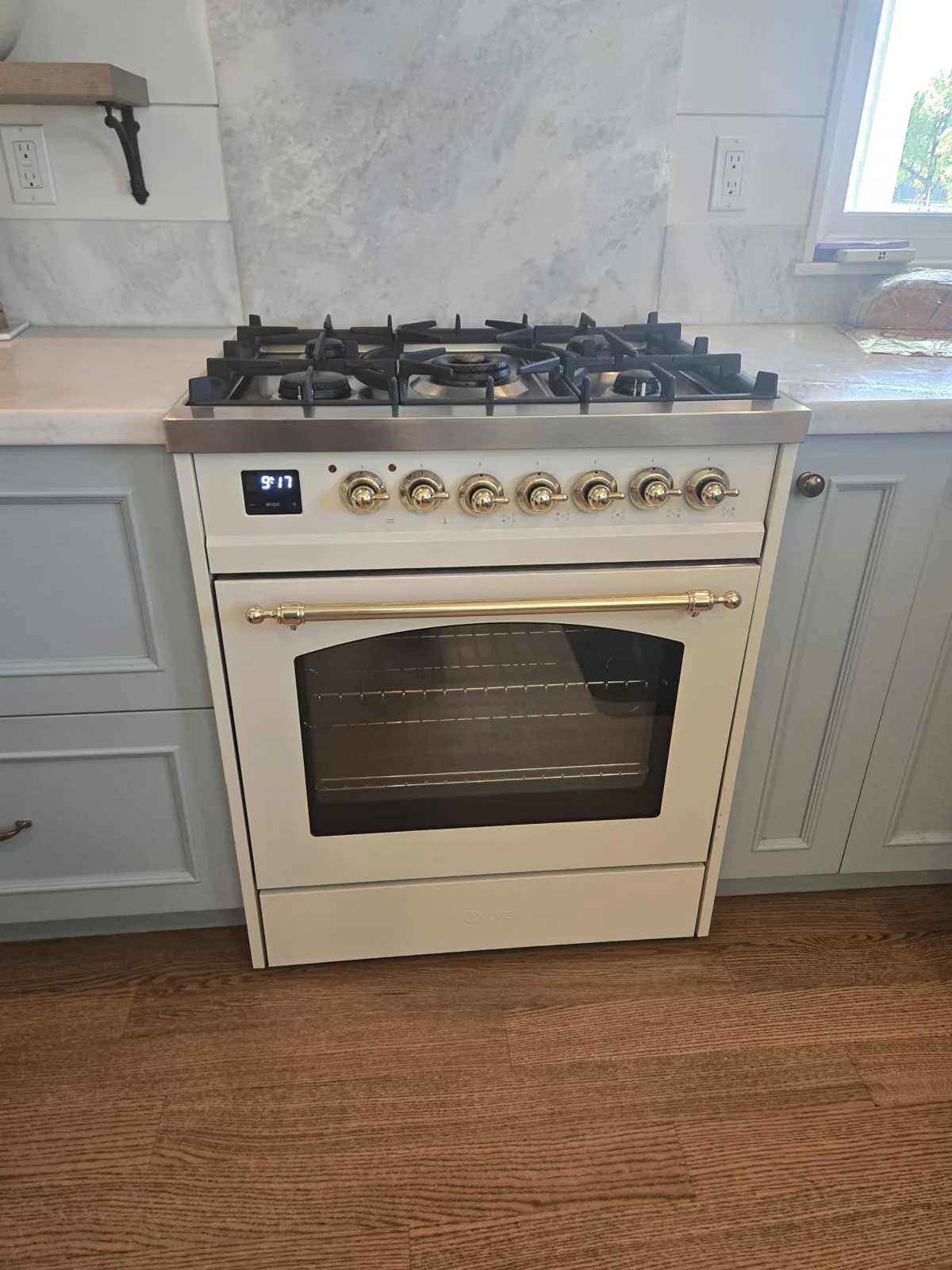 White ILVE gas range with brass-colored controls.
