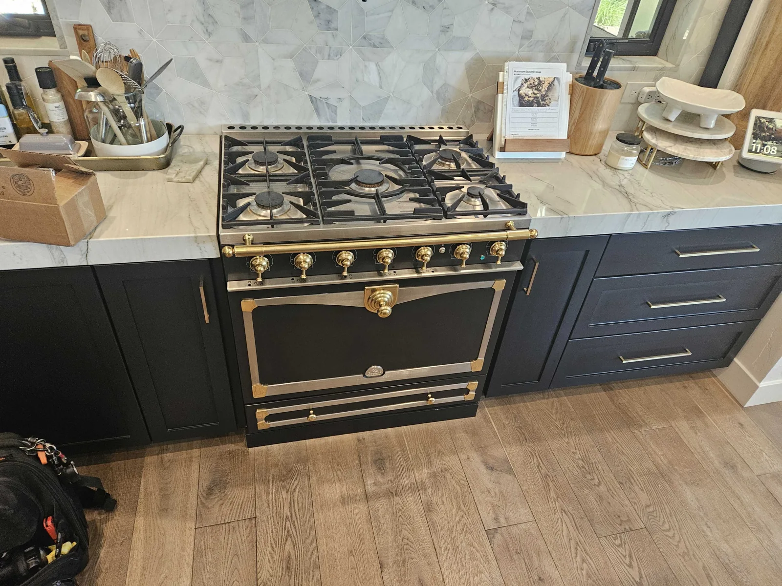 Black and brass La Cornue range installed in a kitchen island.