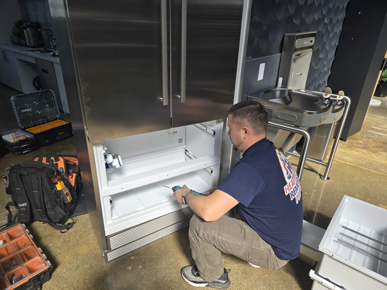 Technician accessing the lower refrigerator compartment.