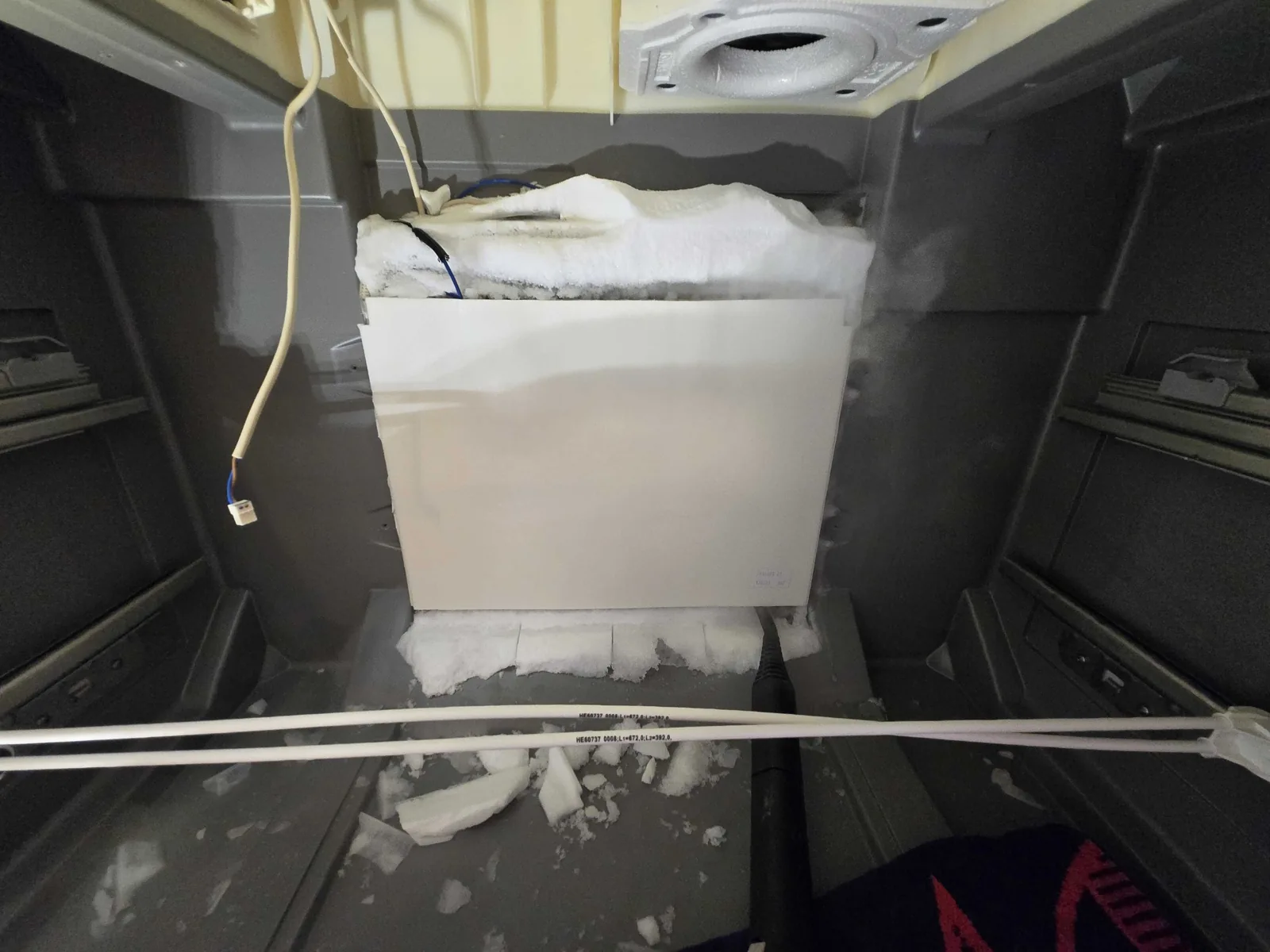 Rear freezer panel opened during service, with ice visible.