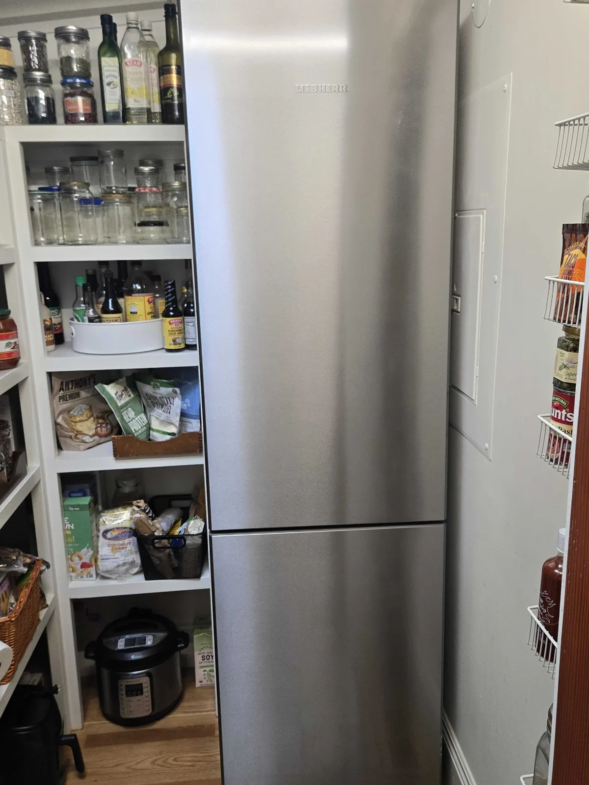 Liebherr refrigerator installed beside pantry shelving.
