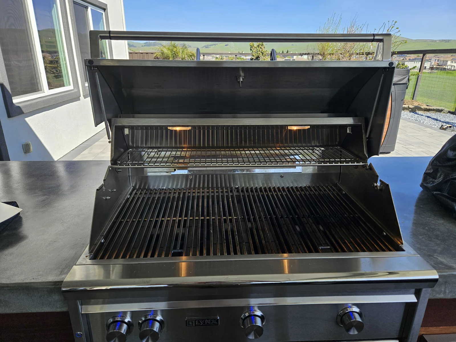 Lynx outdoor grill with the hood open and cooking grates visible.