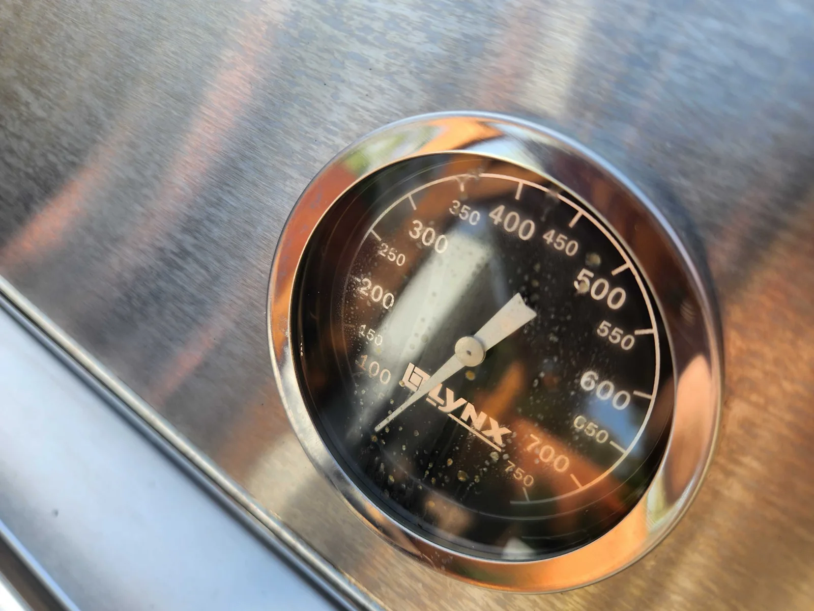 Close-up of a Lynx grill hood thermometer.