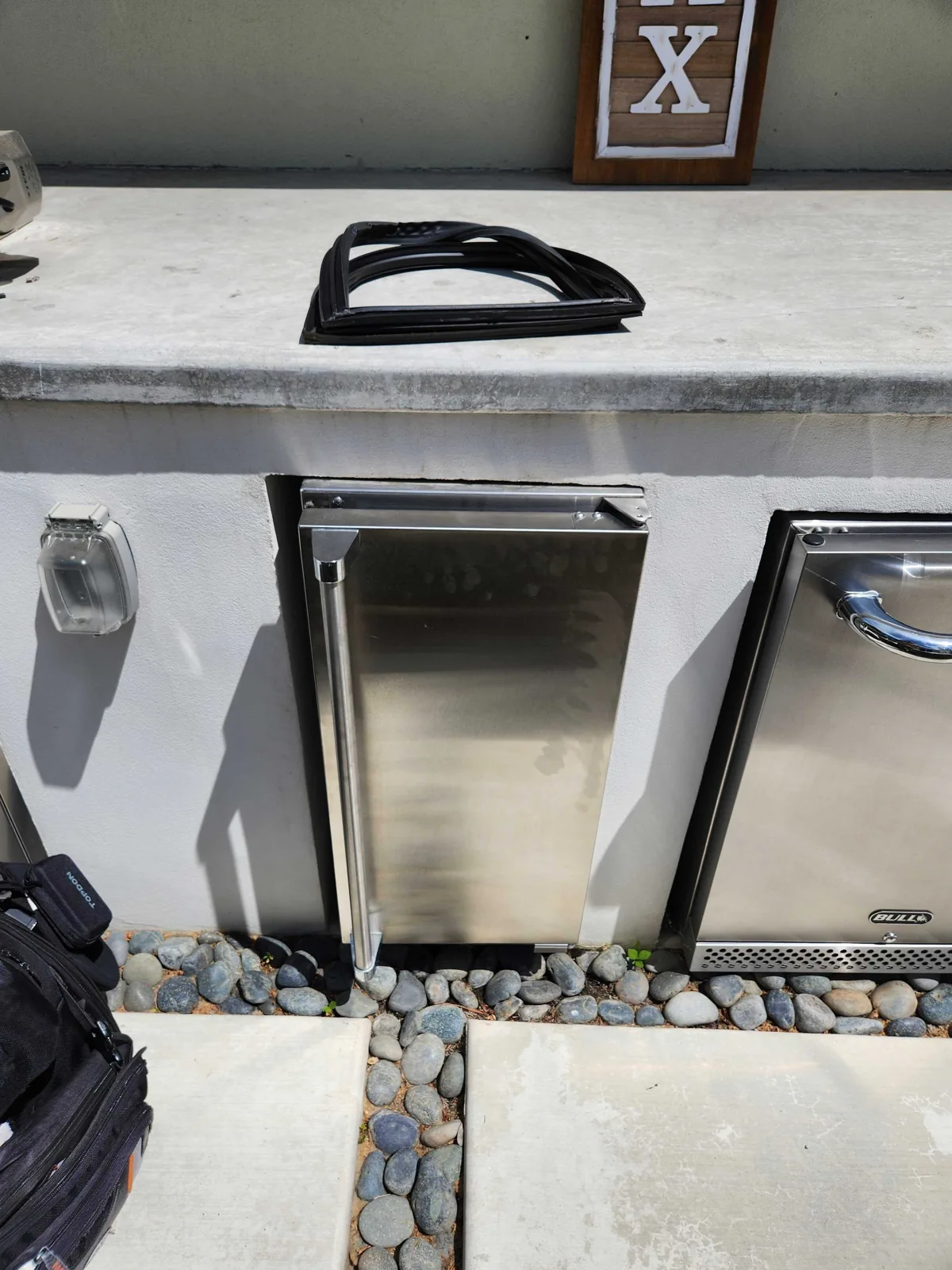 Outdoor undercounter ice maker with its stainless-steel door closed.