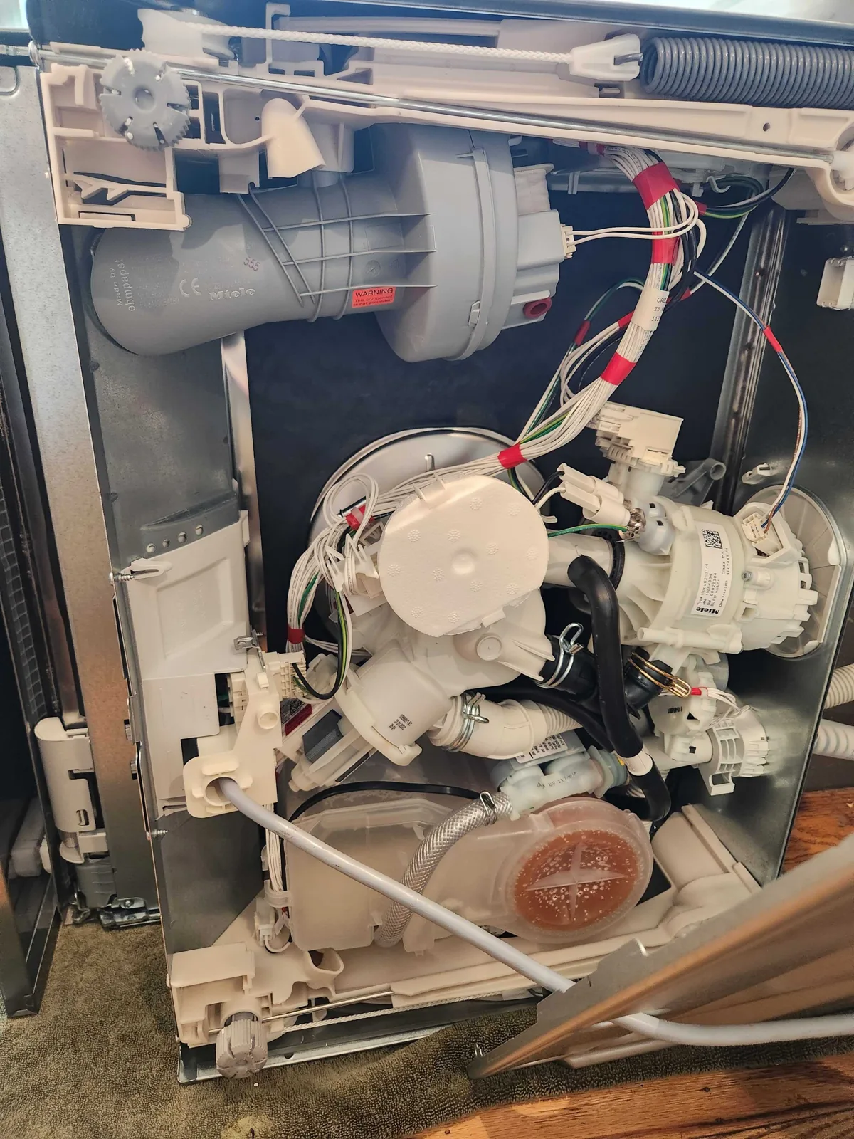Internal components of a Miele dishwasher during service.