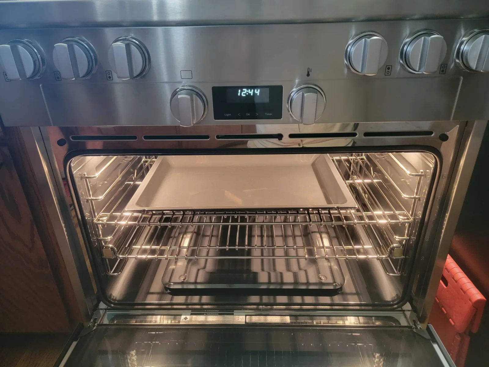 Miele oven with the door open, interior light on and racks visible.