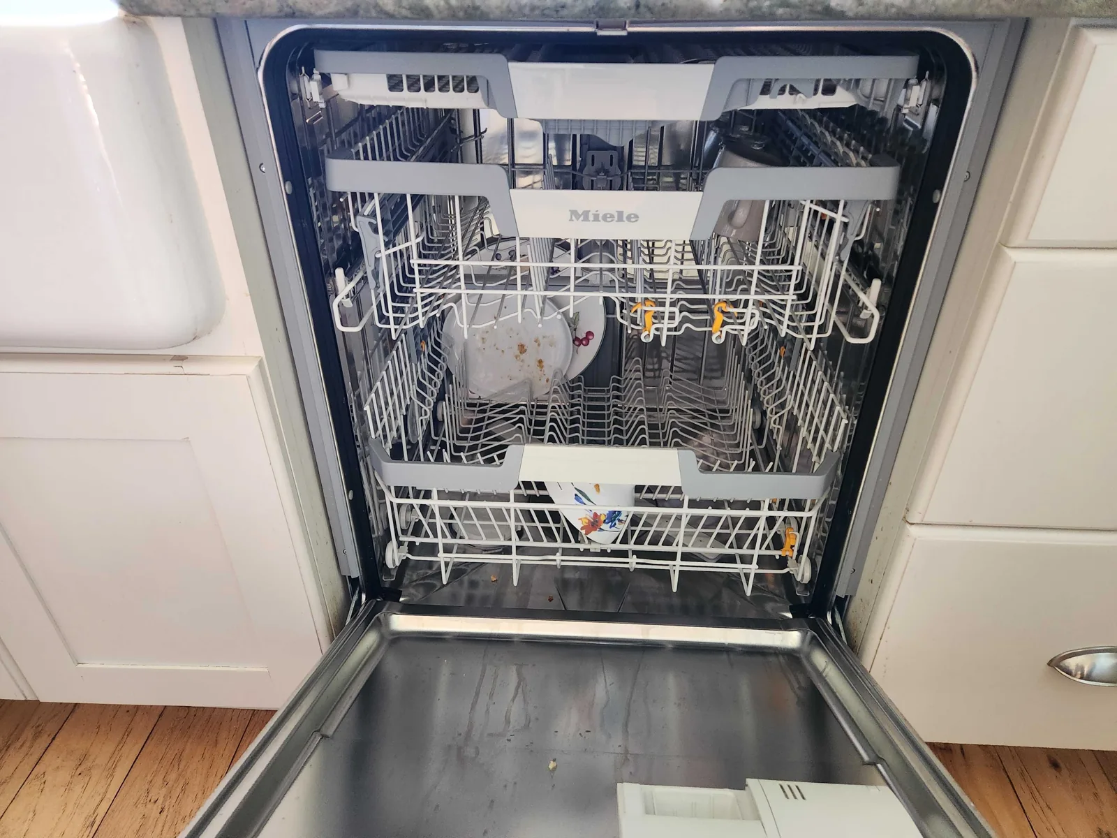 Miele dishwasher with the door open and baskets visible.