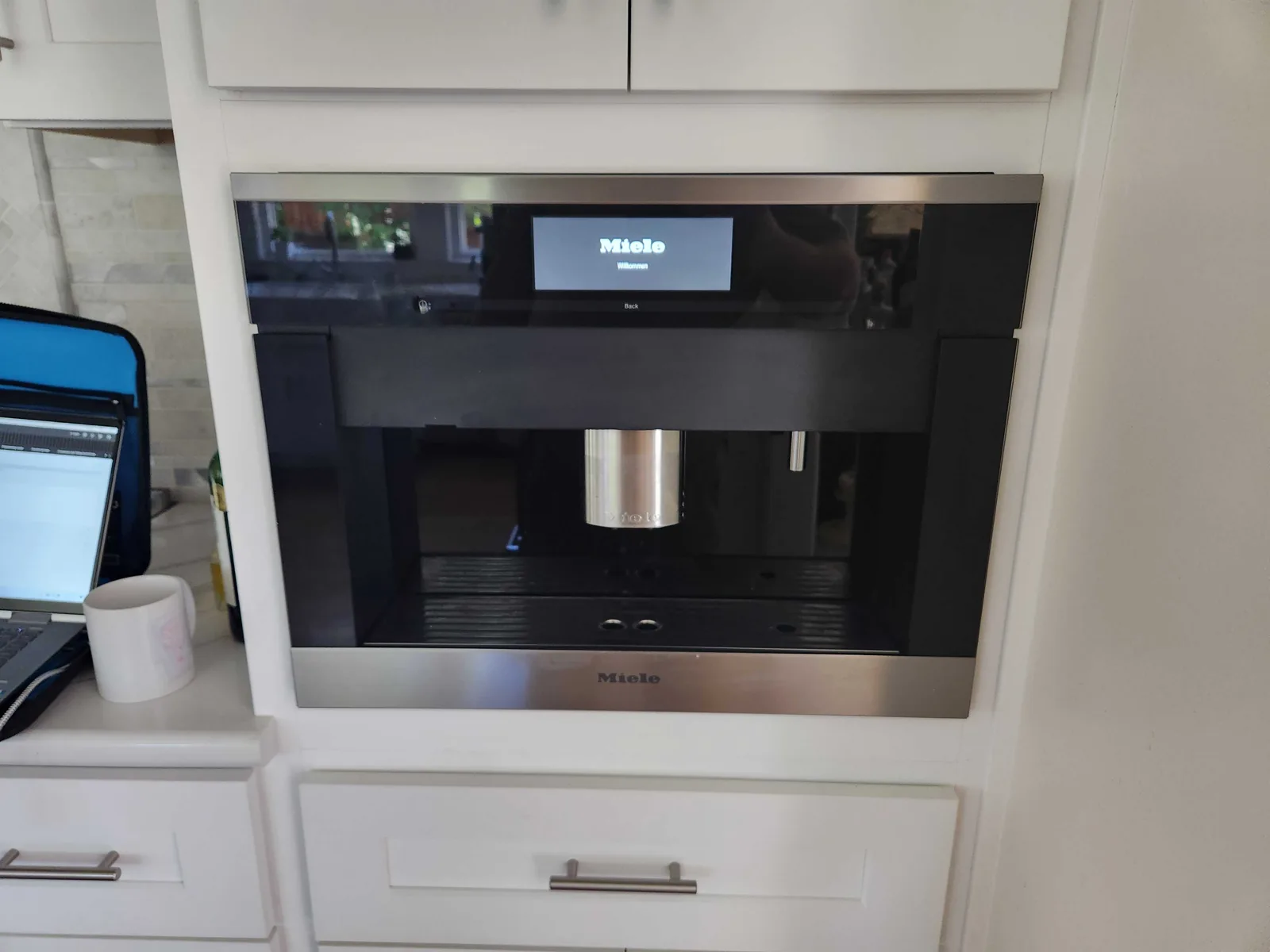 Built-in Miele coffee machine with a cup beneath the dispenser.