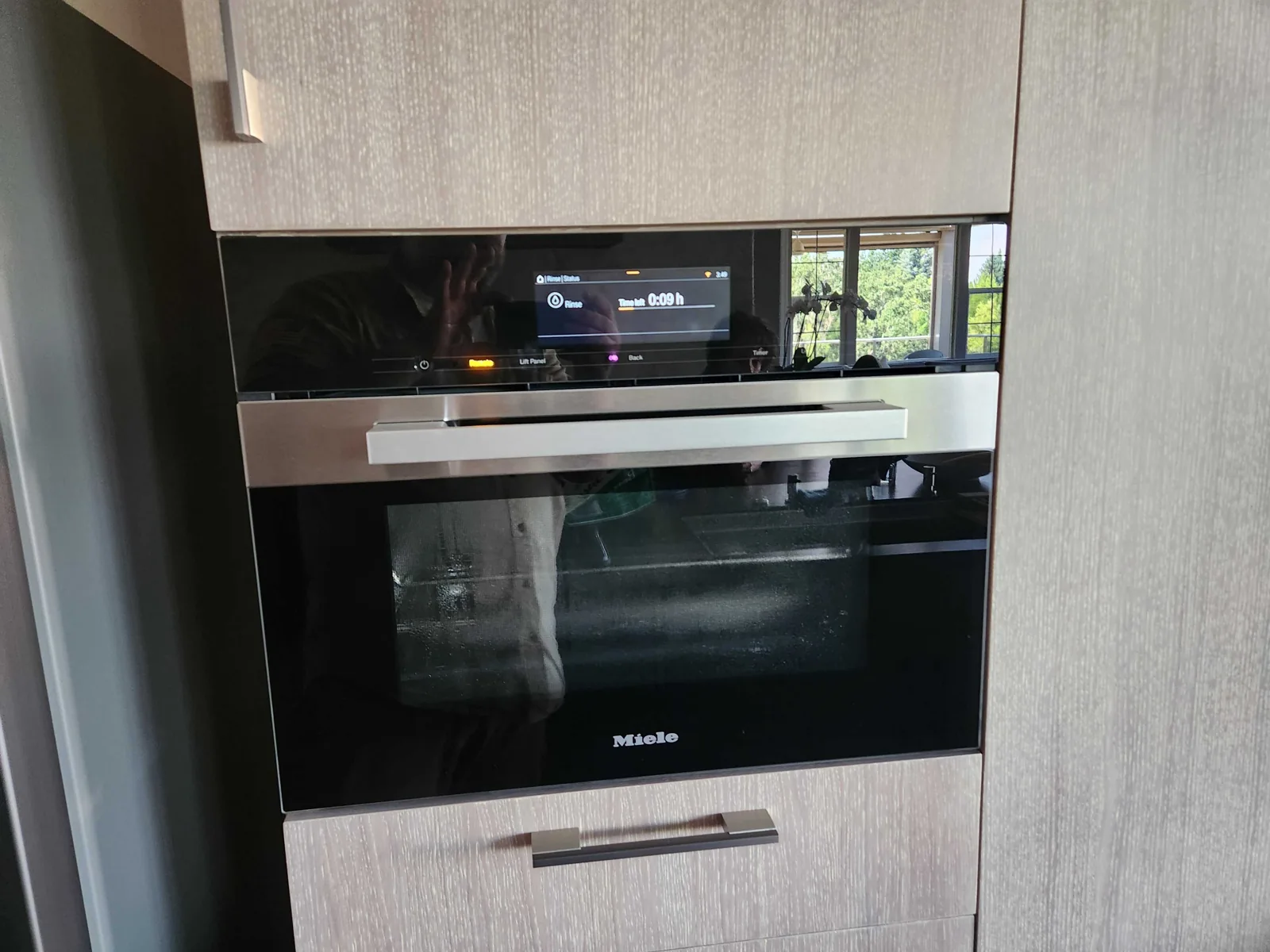 Built-in black-glass Miele oven in kitchen cabinetry.