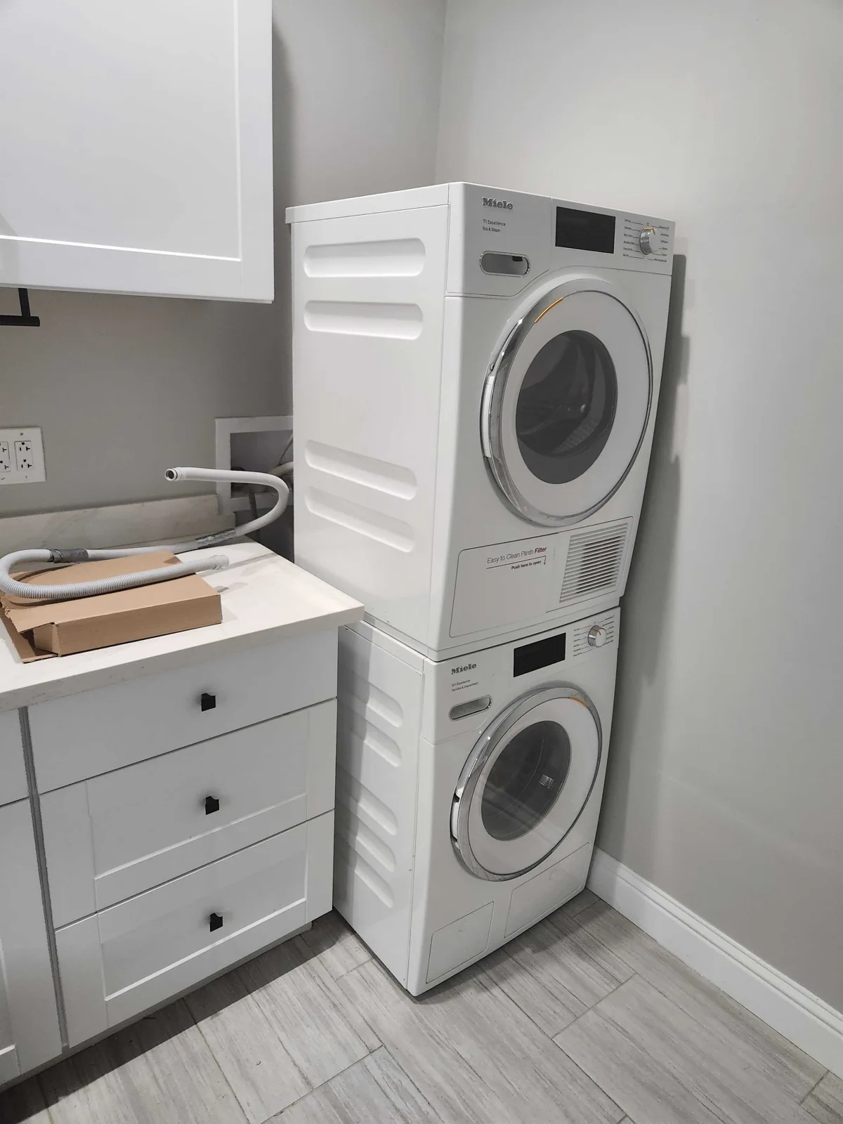 Stacked Miele washer and dryer in a laundry alcove.