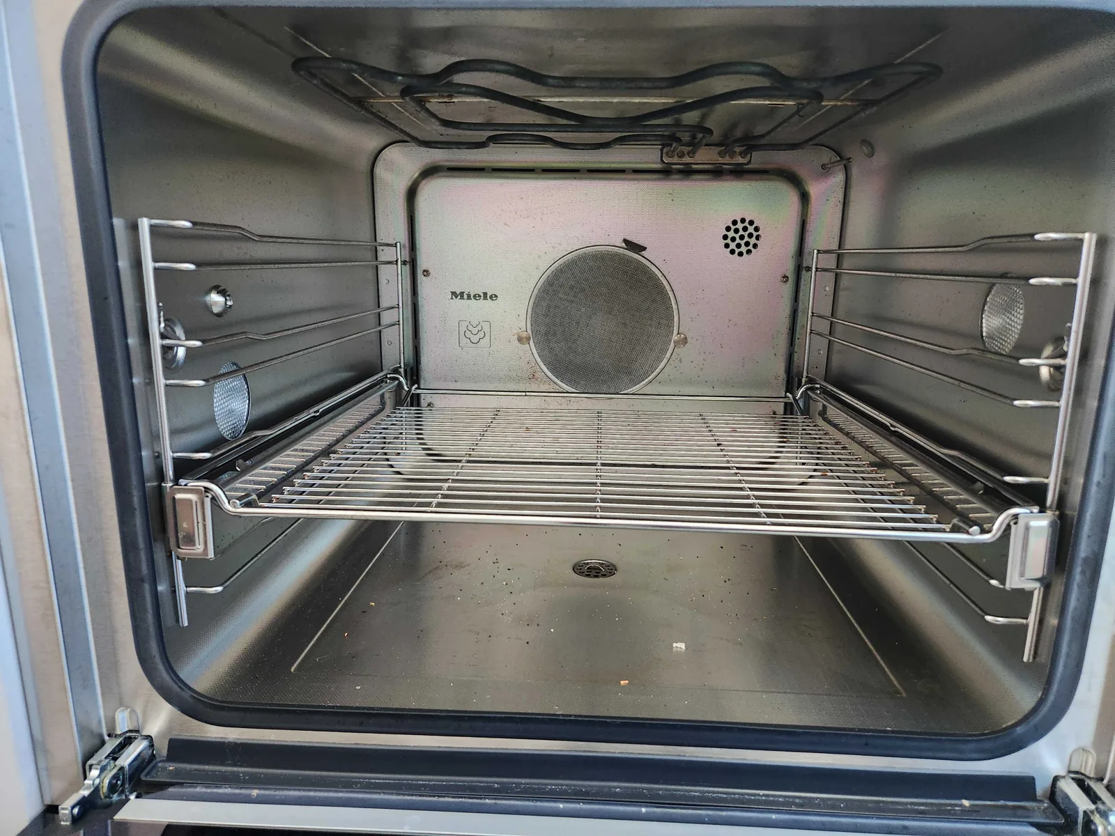 Miele oven cavity with racks and rear fan cover visible.
