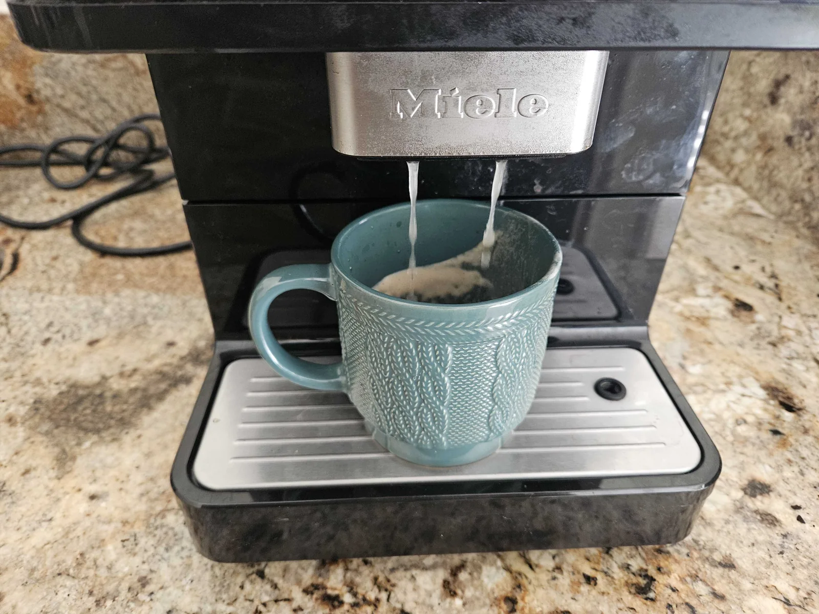 Miele countertop coffee machine dispensing into a cup.