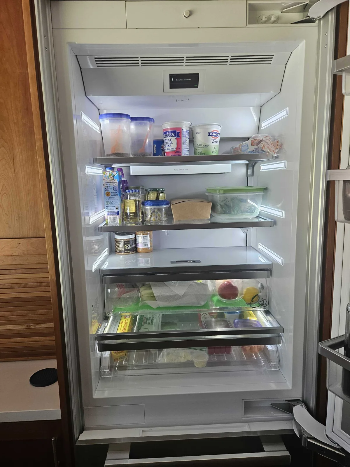 Open Miele refrigerator with interior shelves and drawers visible.