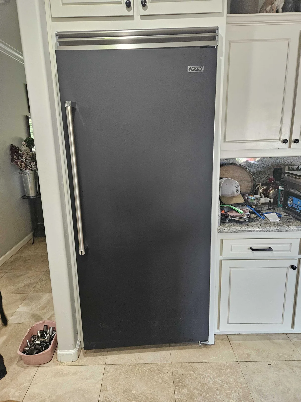 Dark-finish Viking refrigerator installed beside kitchen cabinetry.