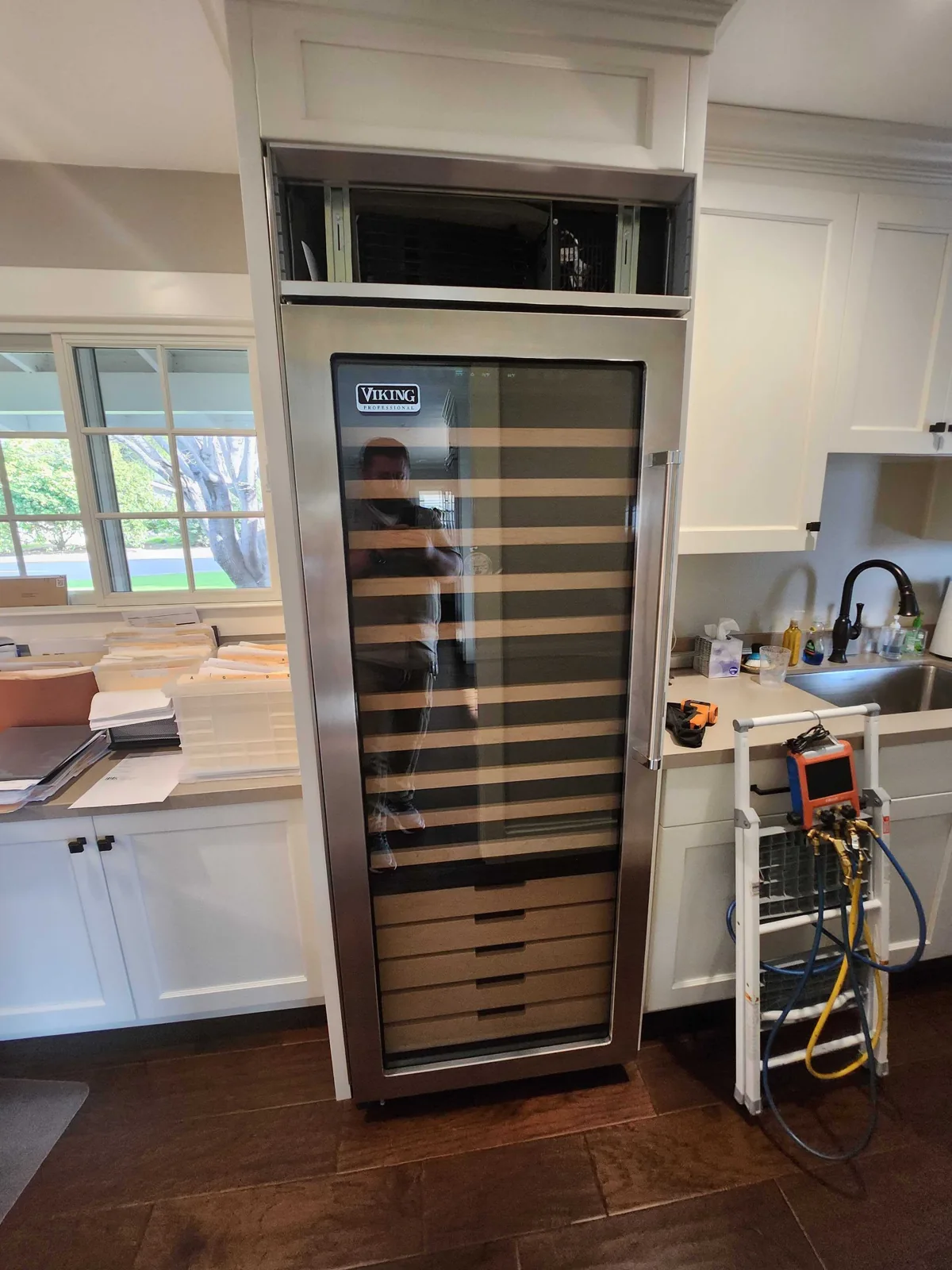 Built-in Viking wine refrigerator with glass door and wooden shelves.