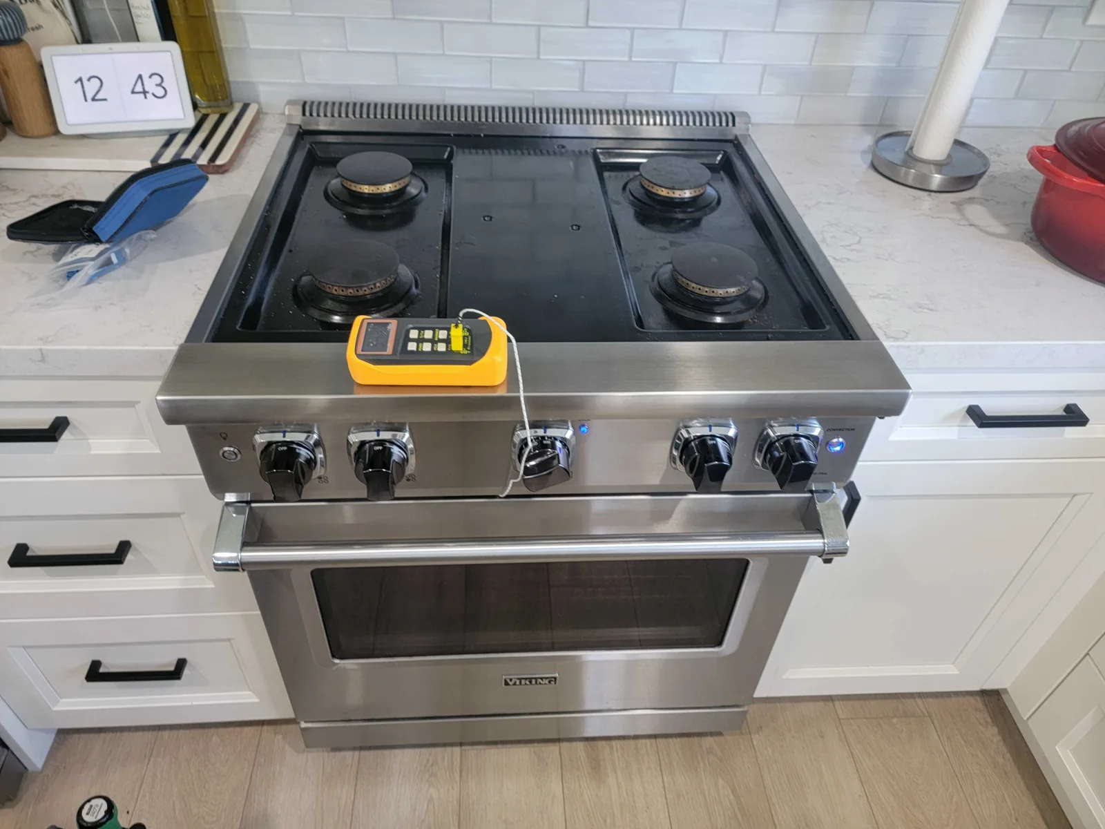Viking range with a handheld measuring instrument resting on the cooking surface.